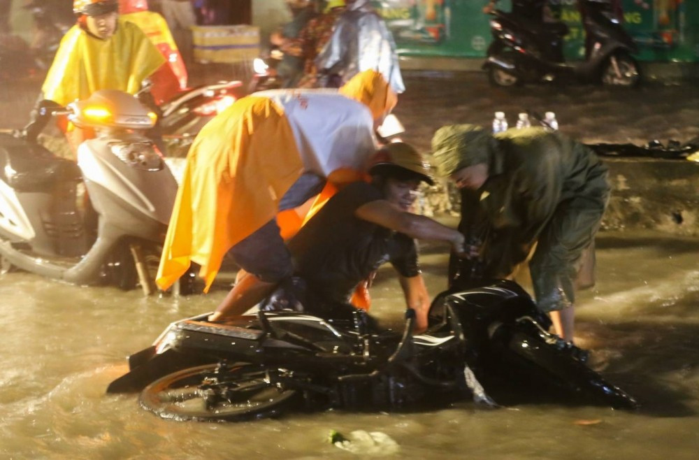 Nhiều người chạy xe máy vấp vào ổ gà trên đường Huỳnh Tấn Phát (quận 7), ngã nhào trong cơn mưa nặng hạt.