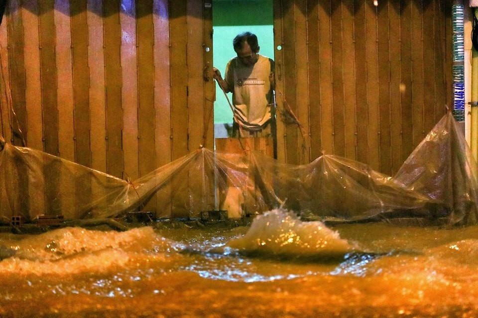 Đến giữa đêm, mưa vẫn trút xuống ở TP HCM. Nhiều nhà dân trên đường Calmette dùng bạt, ván… chắn trước nhà để nước không tràn vào.