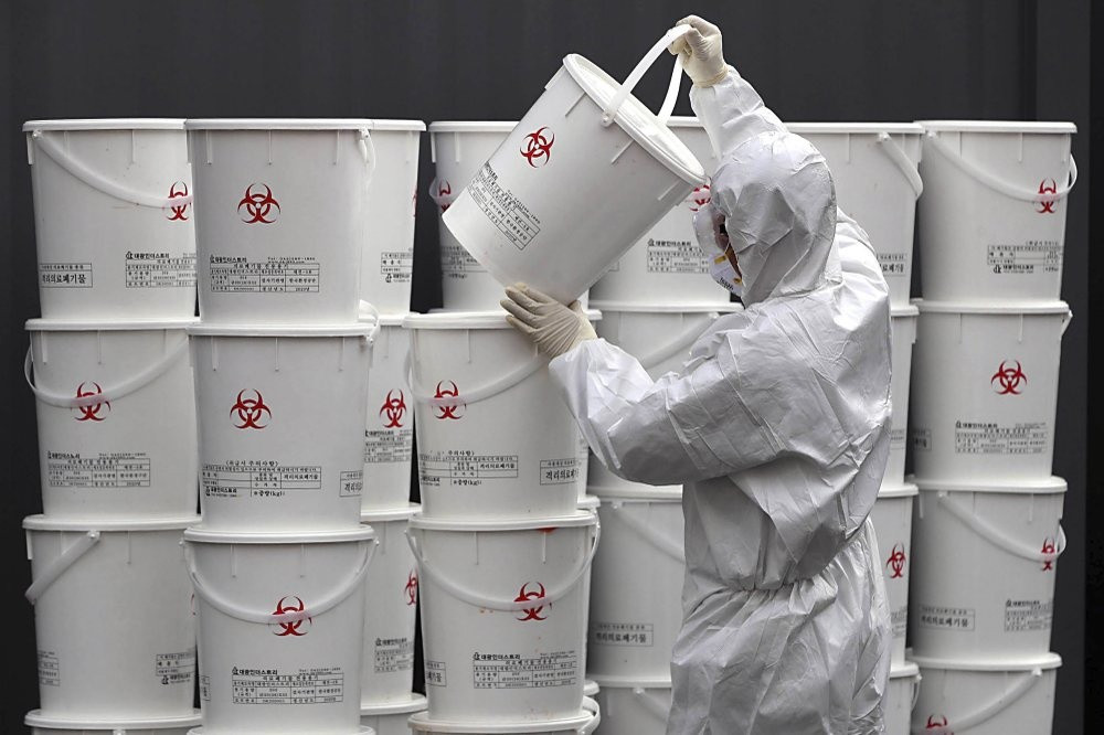 Nhân viên xếp các thùng chứa chất thải y tế từ bệnh nhân tại một trung tâm ở Daegu, Hàn Quốc, hôm 24/2 - Ảnh: AP