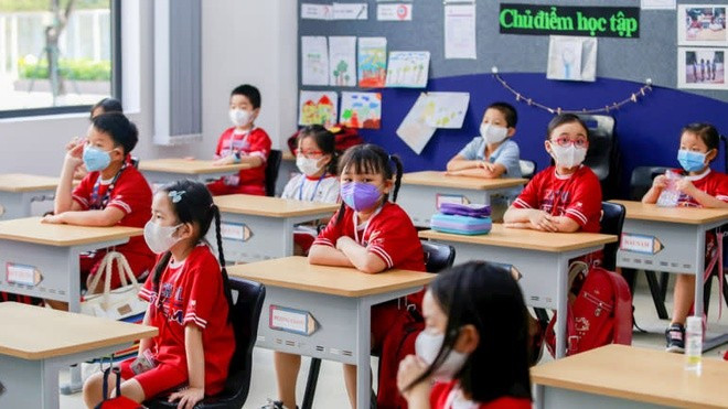 Các em học sinh tiểu học đeo khẩu trang trong ngày đầu tiên quay lại lớp học sau khi Chính phủ chính thức gỡ bỏ lệnh giãn cách xã hội vào hồi tháng 5/2020 - Ảnh: Reuters