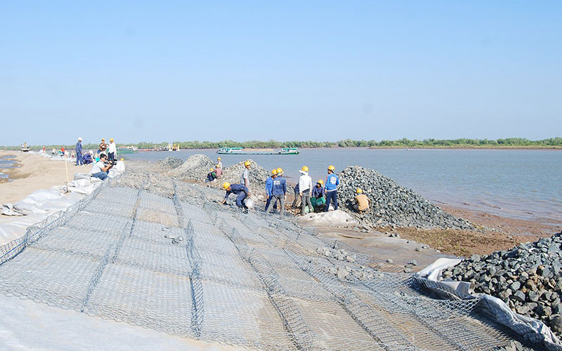 Công nhân lắp đặt các rọ đá chống sạt lở ven bờ cho luồng tàu biển trọng tải lớn vào sông Hậu