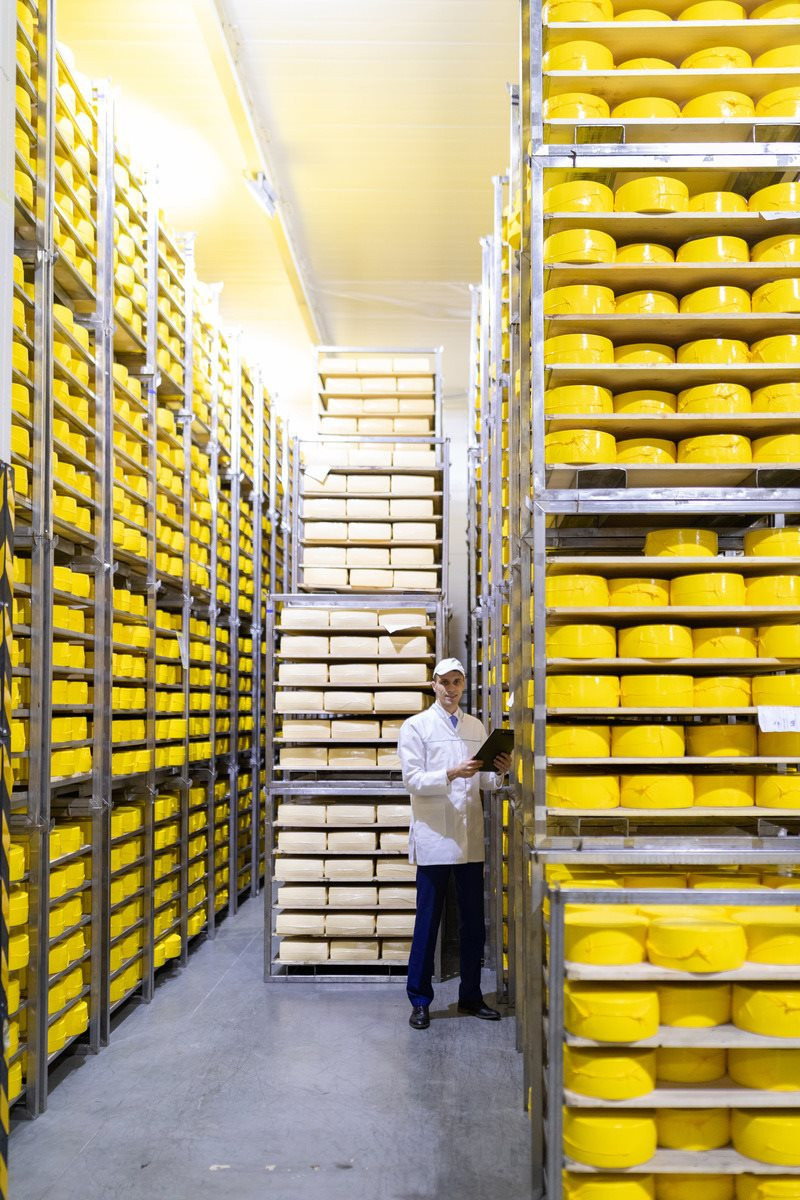 technologist-white-robe-holding-tablet-records-stands-near-shelves-with-cheeses-production-cheese-products-man-cheese-shop-1-.jpg